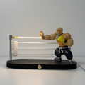 Action figure of a muscular character with a light saber on a stand against a plain background